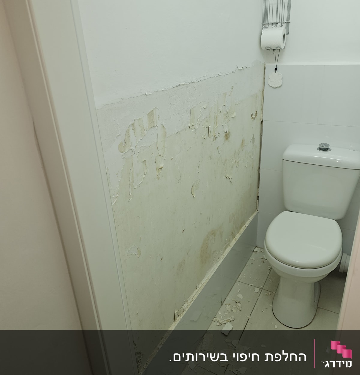 קיר מתקלף בשירותים עם שאריות צבע על הרצפה